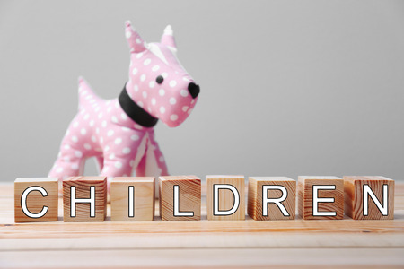 Word children made of wooden cubes and toy dog on wall backgroundの写真素材