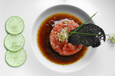 Delicious red fish with sauce and lime slices on white plateの写真素材