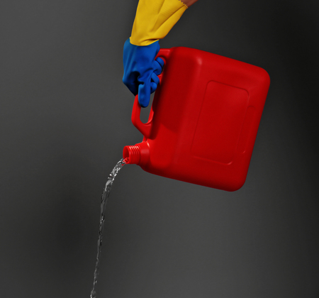Hand holding jerrycan on dark grey backgroundの写真素材