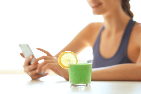 Smoothie drink and girl with phone at tableの写真素材
