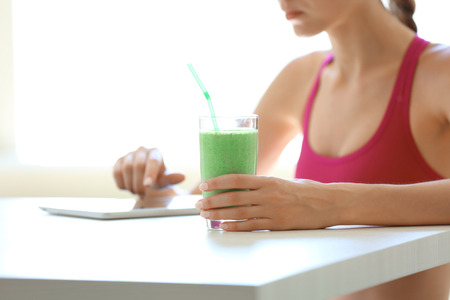 Girl with tablet and smoothie calculating calories on kitchenの写真素材