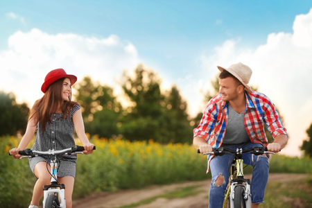 Young couple on bicycles in fieldの写真素材
