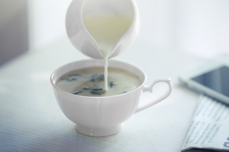 Pouring milk in tea on tableの写真素材