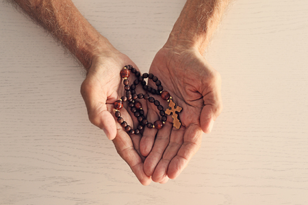 Wrinkled hands with wooden rosaryの写真素材