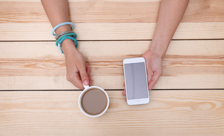 Woman with cellphone and coffee, top viewの写真素材