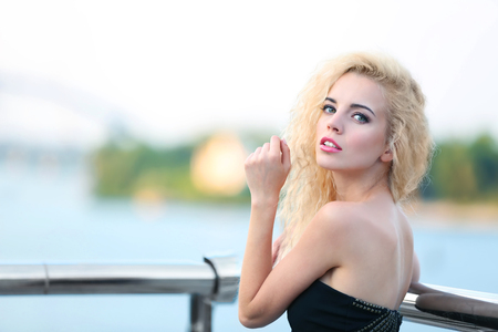 Fashionable young woman posing on river shore backgroundの写真素材