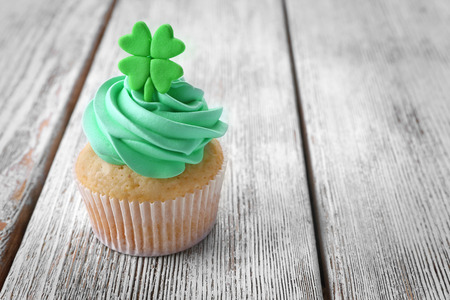 Tasty cupcake with clover on wooden background. Saint Patrics Day conceptの写真素材