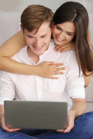 Beautiful couple surfing internet on laptop at homeの写真素材