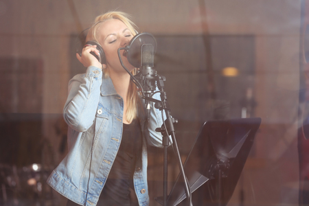 Young woman recording a song in a professional studioの写真素材