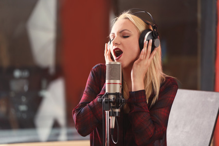 Young woman recording a song in a professional studioの写真素材