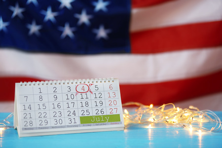Calendar and lights on blurred American flag background. Independence day concept