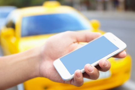 Male hand with cellphone calling taxiの写真素材