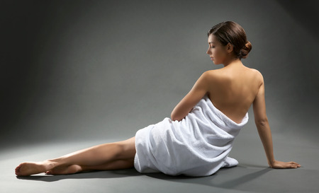 Beautiful girl wrapped in a towel on grey backgroundの写真素材