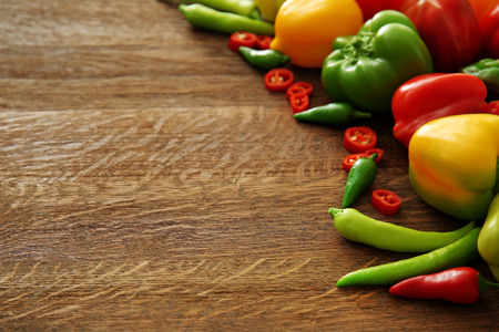 Different sorts of pepper on wooden background