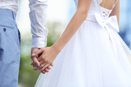Bride and groom holding hands together outdoorの写真素材