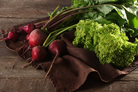 Bunch of young beets on brown napkin and wooden background