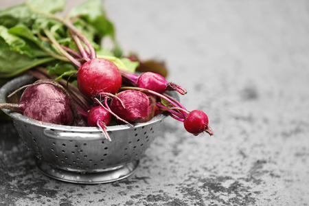 Bunch of fresh beets in a colander on grey backgroundの写真素材