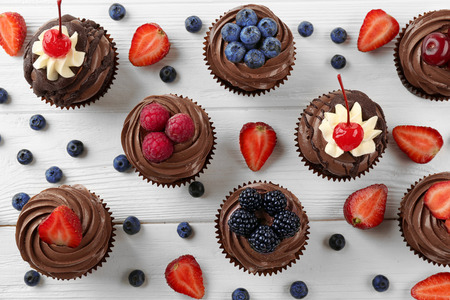Delicious chocolate cupcakes with berries on white table, top viewの写真素材