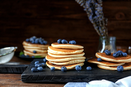 Tasty pancakes with blueberries on cutting board
