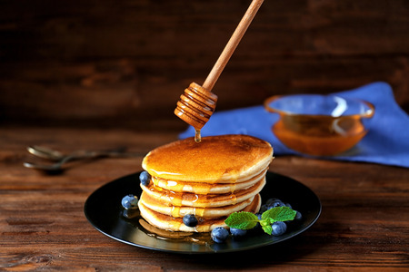 Tasty pancakes with blueberries and honey on tableの写真素材