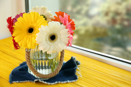 Vase with bouquet of gerbera flowers on window sillの写真素材