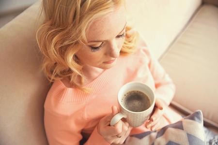 Beautiful girl drinking coffee on couchの写真素材
