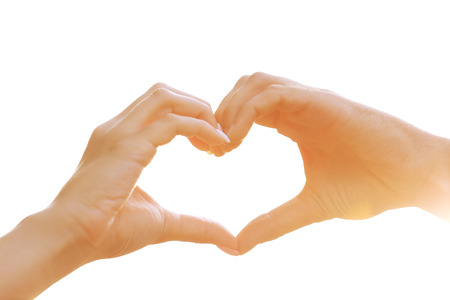 Young couple holding hands in shape of heart on light backgroundの写真素材