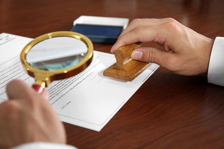 Notary public using stamp and magnifier, close upの写真素材