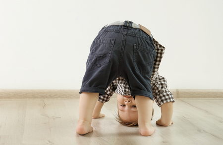 Fashionably dressed baby boy posing on a white wall backgroundの写真素材