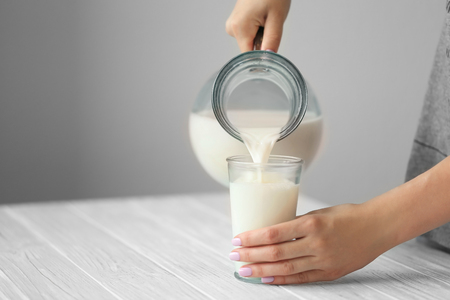 Female hand pouring milk from a jug into a glassの写真素材