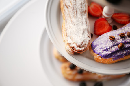Delicious colourful eclairs with berries on dessert stand, closeupの写真素材