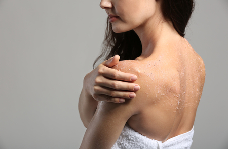 Young woman applying scrub on shoulderの写真素材