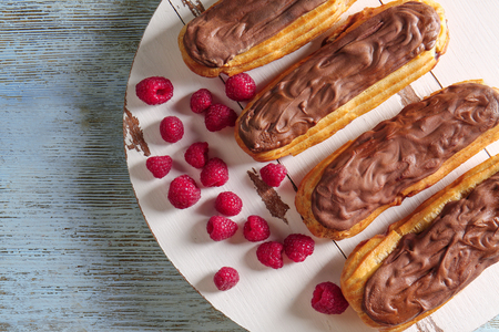 Delicious eclairs with chocolate and raspberry on wooden backgroundの写真素材