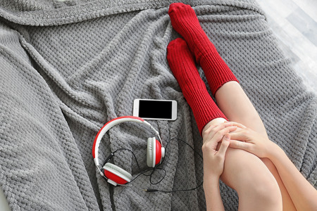 Girl with headphones and phone resting on soft bedの写真素材