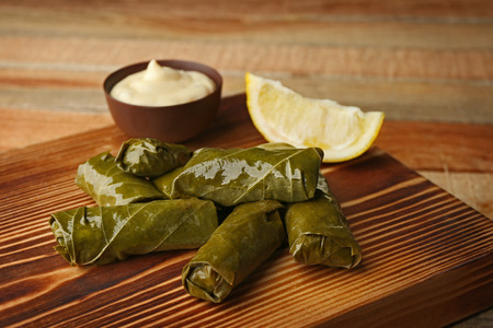 Stuffed delicious Dolma with sauce and lemon on wooden boardの写真素材