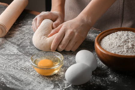 Female hands making dough for pizza on black tableの写真素材