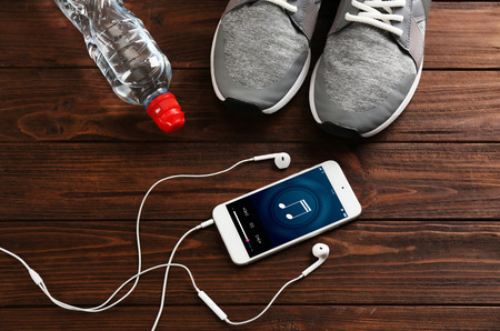 Sport shoes and cellphone on wooden background