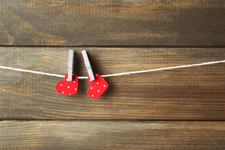 Red hearts hanging on clothespins on wooden backgroundの写真素材