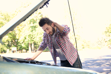 Young handsome man looking under car hoodの写真素材