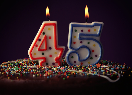 Birthday cake with burning candles on dark backgroundの写真素材