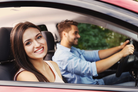 Beautiful young woman looking out of open car window