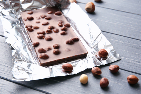 Chocolate bar with nuts in foil on tableの写真素材