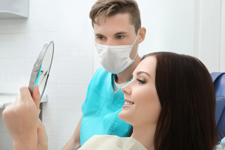 Young woman looking in mirror after dentistryの写真素材