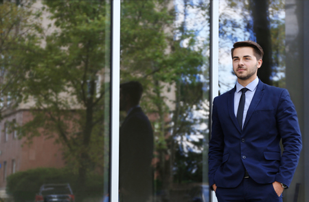 Young businessman on office building backgroundの写真素材
