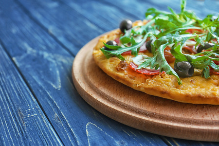 Tasty pizza with mushrooms, cherry tomatoes, olives and arugula on blue wooden backgroundの写真素材