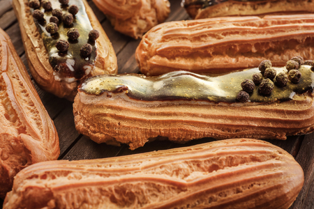 Delicious eclairs on wooden cutting board closeup