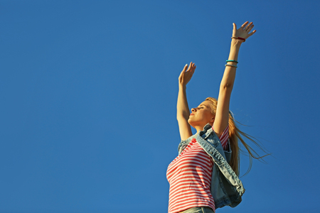 Happy young woman on blue sky backgroundの写真素材