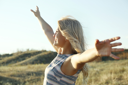 Happy young woman on blue sky backgroundの写真素材