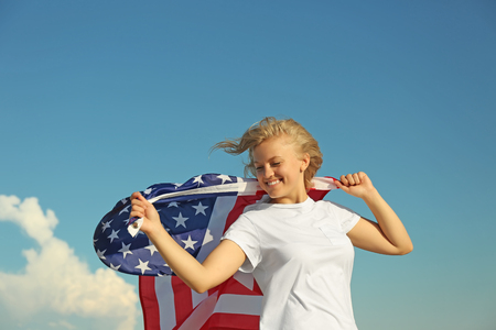 Young woman holding American flag on blue sky backgroundの写真素材