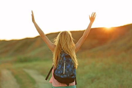 Young woman with raising hands on blue sky backgroundの写真素材